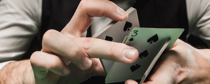 Blackjack Händler, der ein Kartenspiel mit 3 Pik an der Unterseite hält